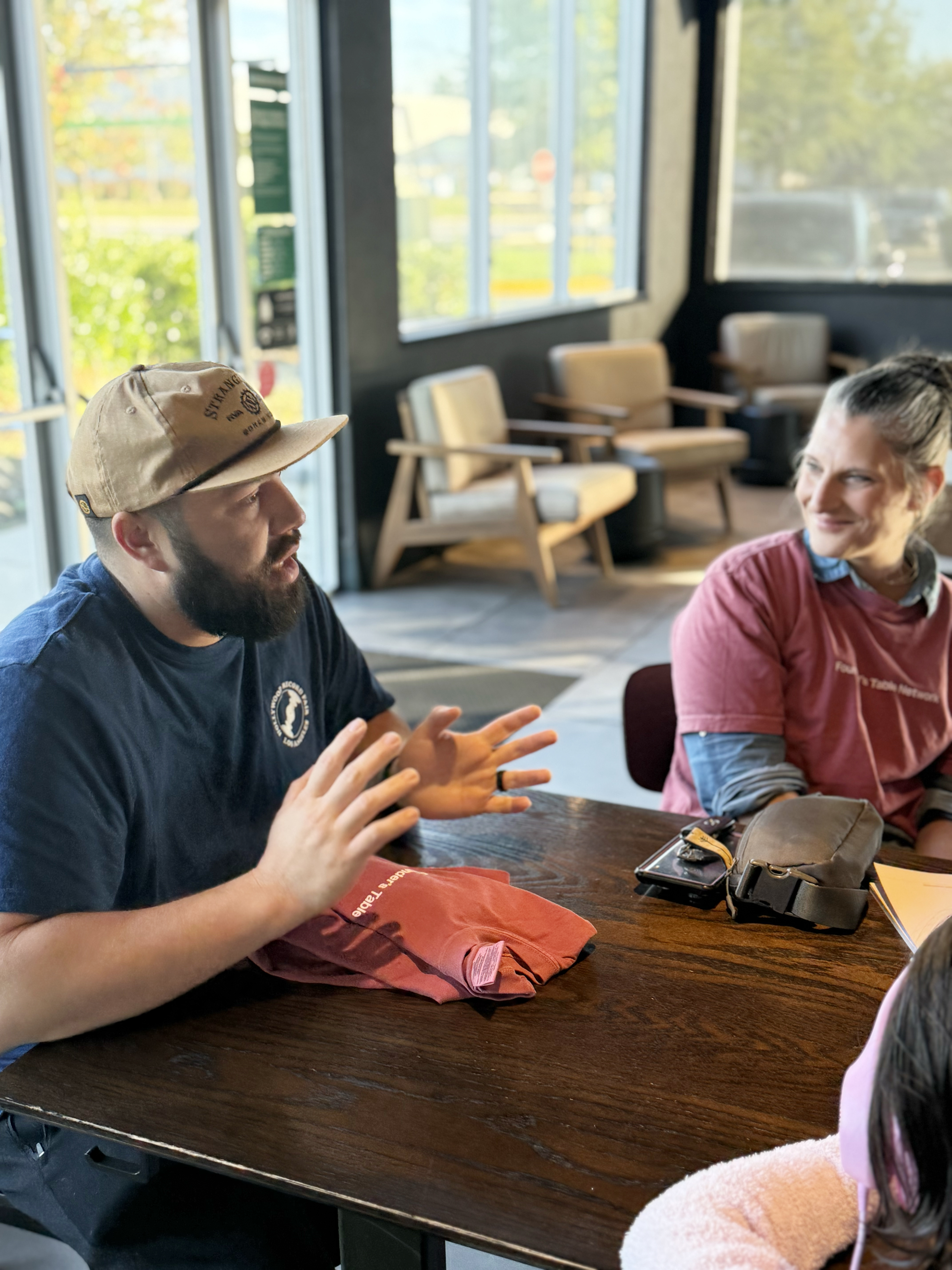 Two smiling meetup attendees with a Founder's Table t-shirt laid out on the table