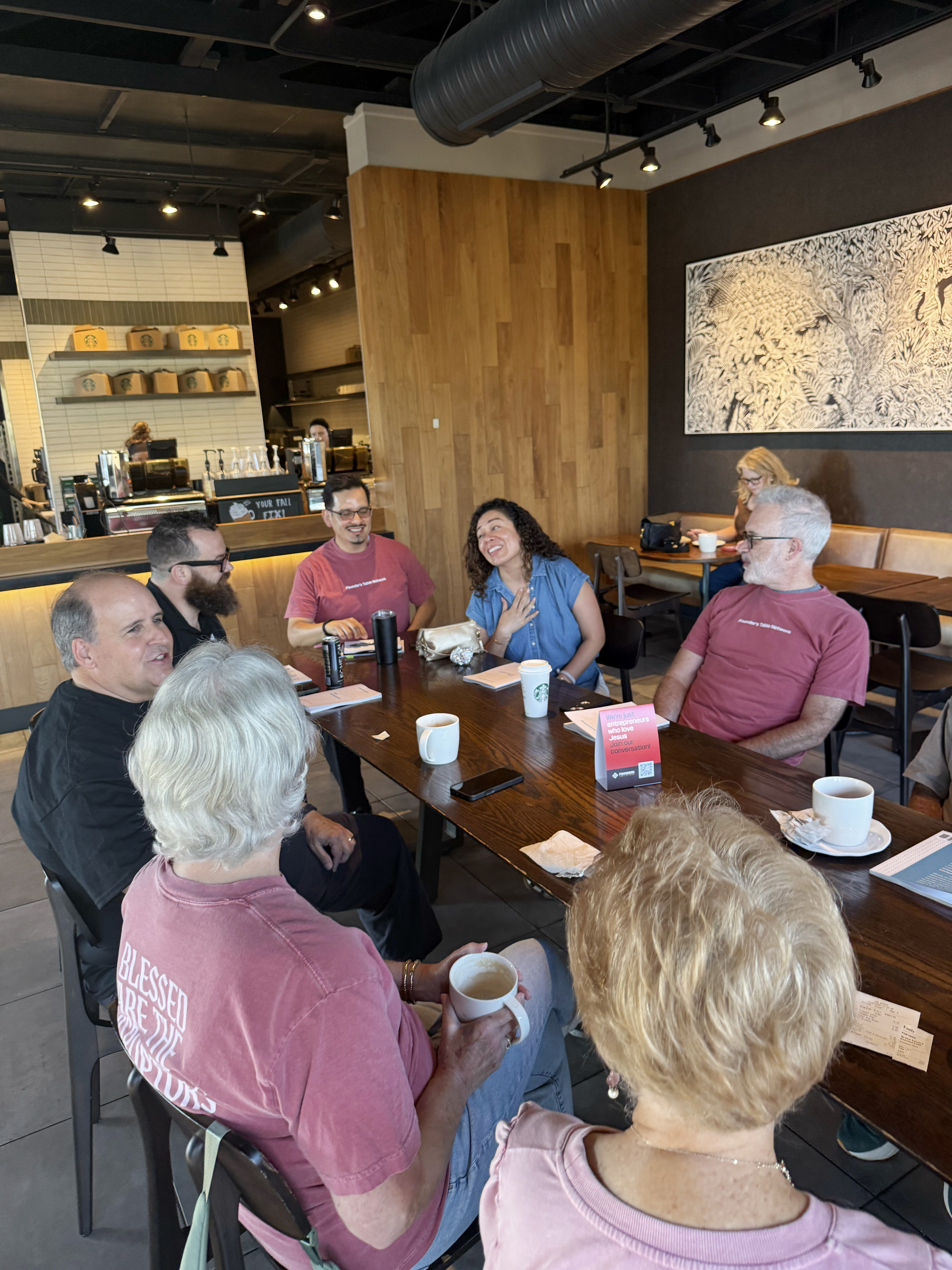 A group of entrepreneurs at a meetup, several wearing Founder's Table Network and Blessed Are The Disruptors t-shirts